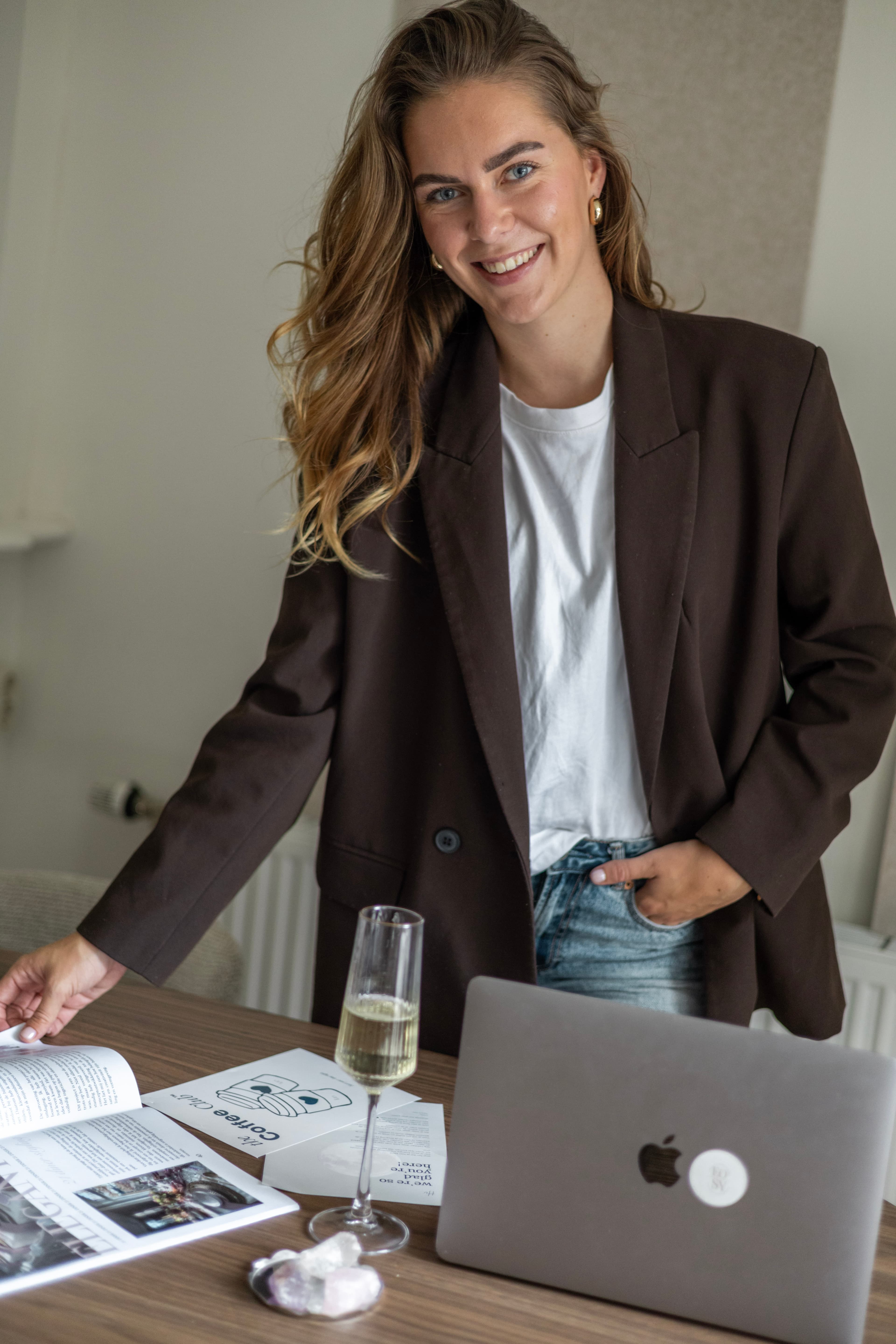 Rianda Meinardi bij een tafel met een laptop en een glas champagne